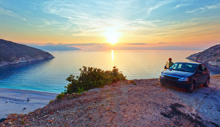 Sea sunset view of Myrtos Beach and woman near car (Greece,  Kefalonia, Ionian Sea).の写真素材