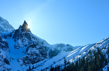 Winter rocky mountain view and sun peeks out from behind the rocks.の写真素材