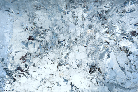 Glacial transparent wall of ice with interesting drawings and patterns . Closeup, background.