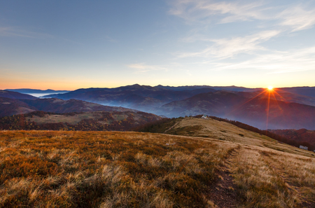First beams of rising sun in autumn Carpathian. Mountain top daybreak landscape.の写真素材