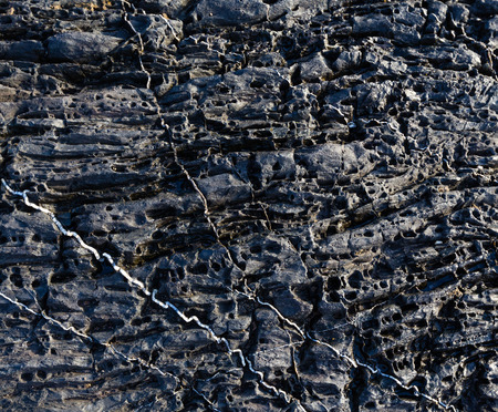 Part of rock closeup with white stripes of another geological material.