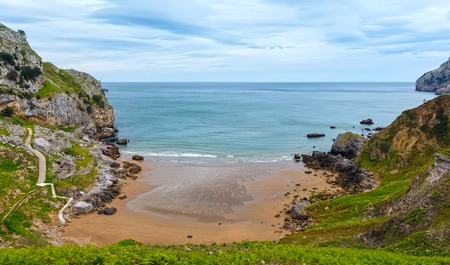 Spring sea rocky coast with stone stairway going down to sandy beach (San Julian Beach, Liendo, Cantabria, Spain).の写真素材
