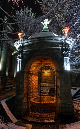 Beautiful night winter Lviv city (Ukraine) illuminated cityscape. Well of Saint John of Dukla in the courtyard of Bernardine Church and monastery (church of St. Andrew), build in 17th century.の写真素材