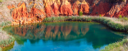 The lake in old bauxite's red soils quarry cave in Apulia, Otranto, Salento, Italy. The digging was filled with natural waters. Two shots stitch high-resolution panorama.の写真素材