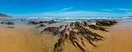 Rock formations on sandy beach (Algarve, Costa Vicentina, Portugal). Summer Atlantic ocean coast panorama.の写真素材