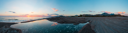 Beautiful sea sunset panorama with picturesque sky reflection in water. Ancient Cirella town ruins and mountain villages on hill tops. Not far from Scalea, Cosenza, Italy.の写真素材