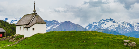 Lovely small old Church in Bettmeralp Alps mountain village, Switzerland. Summer cloudy panorama view.の写真素材