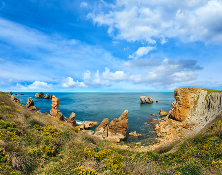Beautiful blossoming Atlantic Ocean coastline landscape with yellow flowers in front (near Arnia Beach, Biskaya, Cantabria, Spain). Two shots stitch panorama.の写真素材