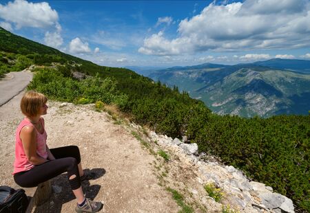 Woman on wooden bench over picturesque summer Tara Canyon in mountain Durmitor National Park, Montenegro, Europe, Balkans Dinaric Alpsの写真素材