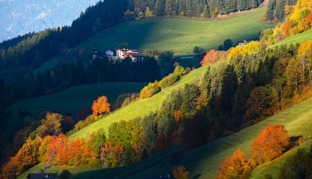 Hills. Light and shadow. Autumn morning mountain village environs with grassy hills, small groves in first sun light, deep shadows on slopes. Picturesque seasonal and countryside beauty concept scene.の写真素材