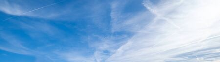 White fluffy cirrus and cirrocumulus clouds in deep blue azure sky and sunlight glow in sky. Summer good weather concept background.の写真素材