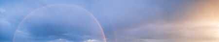 Summer sunset after rain sky panorama with fleese purple clouds and rainbow. Evening dusk good weather natural background.の写真素材