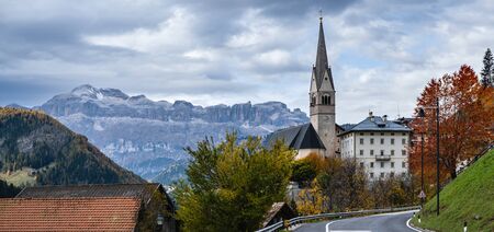 Autumn alpine Dolomites scene, Sudtirol, Italy. Peaceful village and old church view from road, Localita Soraru, Livinallongo del Col di Lana, Belluno, Italy. Piz Boe mountain top in far.の写真素材