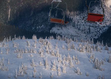 Alpine resortr ski lift with seats going over the sunset mountain skiing freeride slopes and fir tree grovesの写真素材