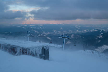 Alpine resortr ski lift with seats going over the sunset mountain skiing slopes in extremally windy...