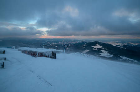 Alpine resortr ski lift with seats going over the sunset mountain skiing slopes in extremally windy...