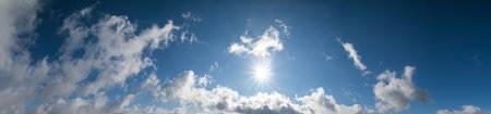 Blue sky with clouds in sunlight, wide cloudscape background panorama