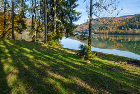 Forest meadow on shore of picturesque lake. Vilshany water reservoir on the Tereblya river, Transcarpathia, Ukraine. Beautiful autumn day in Carpathian Mountains.の写真素材