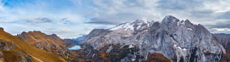 Autumn evening alpine Dolomites mountain scene from hiking path betwen Pordoi Pass and Fedaia Lake, Trentino, Italy. Snowy Marmolada Glacier and Fedaia Lake in far.の写真素材