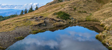 Small picturesque lake with clouds reflections at the  Strymba Mount. Beautiful autumn day in Carpathian Mountains near Kolochava village, Transcarpathia, Ukraine.の写真素材