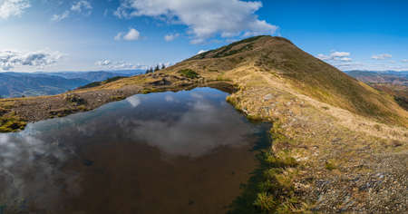 Small picturesque lake with clouds reflections at the  Strymba Mount. Beautiful autumn day in Carpathian Mountains near Kolochava village, Transcarpathia, Ukraine.の写真素材
