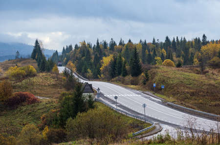 Hazy and overcast Carpathian Mountains and highway on mountain pass, Ukraine.