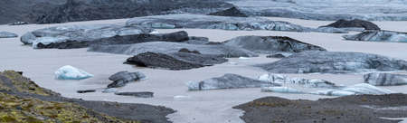 Glacier tongue slides from the VatnajÃ¶kull icecap or Vatna Glacier near subglacial ÃrÃ¦fajÃ¶kull volcano, Iceland. Glacial lagoon with ice blocks and surrounding mountains.の写真素材