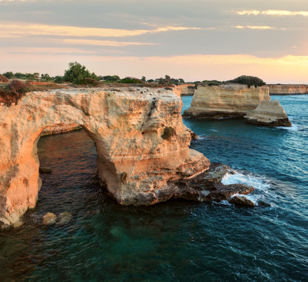 Sunrise seascape with cliffs, rocky arch and stacks (faraglioni), at Torre Sant Andrea, Salento sea coast, Puglia, Italyの写真素材