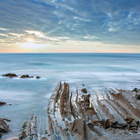 Twilight ocean coast with ribbed stratiform rock formations. (Atlantic Ocean, Spain).の写真素材