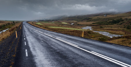 Highway road and mountain view during auto trip in Iceland. Spectacular Icelandic landscape with  scenic nature: highland mountains, fields, clouds, glaciers, waterfallsの写真素材