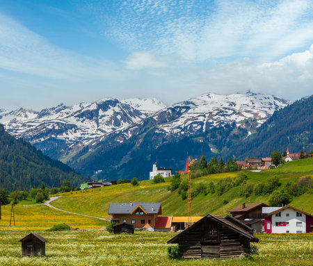 Summer Alpine mountain country view with grassy meadow and road to village (Austria)の写真素材