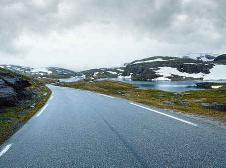 Summer mountain misty landscape with road, lake and snow (Norway, Aurlandsfjellet).の写真素材