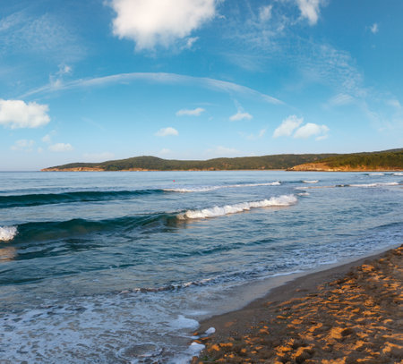 Beautiful sea coast evening view from beach with surf waves and sun reflection on sand.の写真素材