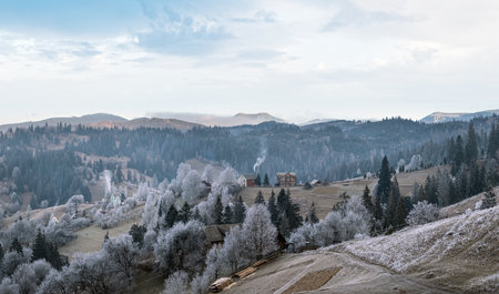 Winter coming. Picturesque foggy and moody morning scene in late autumn mountain countryside with hoarfrost on grasses, trees, slopes. Ukraine, Carpathian Mountains.の写真素材