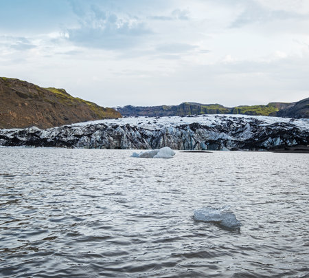 Solheimajokull picturesque glacier in southern Iceland. The tongue of this glacier slides from the volcano Katla. Beautiful glacial lake lagoon with blocks of ice and surrounding mountains.の写真素材