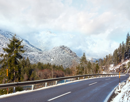 The road along the river and snow-covered mountain slopes (Austria, Tirol).の写真素材