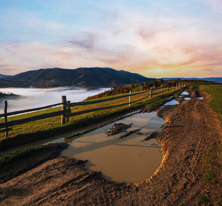Hazy and overcast autumn Carpathian Mountains and dirty countryside path, Ukraine.の写真素材