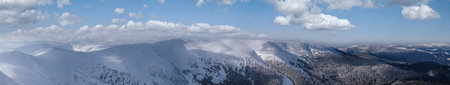 Snow and wind formed ice formations covered winter mountain plateau, tops with snow cornices in far. Magnificent sunny day on picturesque beautiful alpine ridge.の写真素材
