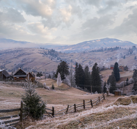 Winter coming. Last days of autumn, morning in mountain countryside peaceful picturesque hoarfrosted scene. Dirty road from hills to the village. Ukraine, Carpathian mountains.の写真素材