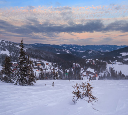 Picturesque winter windy and cloudy morning alps. View of famous Ukrainian Dragobrat ski resort from Svydovets mountain ridge.の写真素材