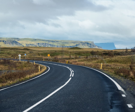 Highway road and mountain view during auto trip in Iceland. Spectacular Icelandic landscape with  scenic nature: fjords, fields, clouds, glaciers, waterfalls.の写真素材