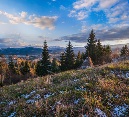 Late autumn mountain pre sunset scene with snow covered tops in far. Picturesque traveling, seasonal, nature and countryside beauty concept scene. Carpathians, Ukraine.の写真素材