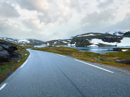 Summer mountain misty landscape with road, lake and snow (Norway, Aurlandsfjellet).の写真素材