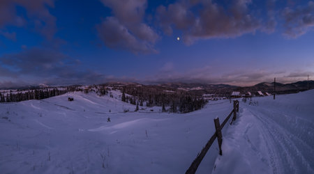 Night countryside hills, groves and farmlands in winter remote alpine mountain village. Ukraine, Voronenko.の写真素材