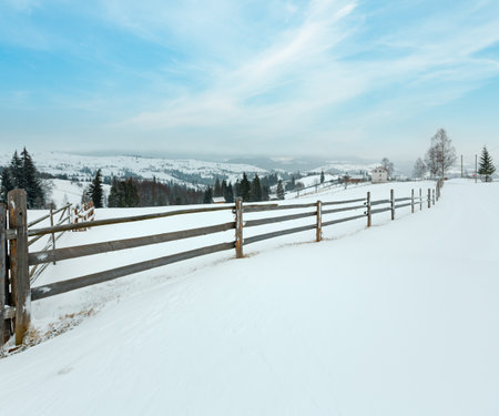 Early morning winter mountain village landscape (Jablunytsia village, Carpathian Mountains, Ukraine). Overcast windy bad weather with some blizzard.の写真素材