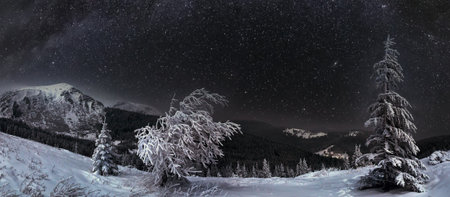 Night winter mountain landscape in full moon moonlight and house with illuminated windowsの写真素材