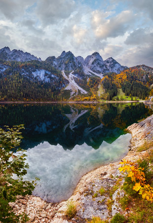 Sunny idyllic colorful autumn alpine view. Peaceful mountain lake with clear transparent water and reflections. Gosauseen or Vorderer Gosausee lake, Upper Austria.の写真素材