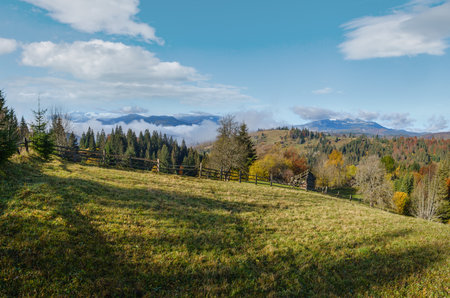 Late autumn mountain morning scene with snow covered tops in far and foggy clouds in valleys. Picturesque traveling, seasonal, nature and countryside beauty concept scene. Carpathians, Ukraine.の写真素材