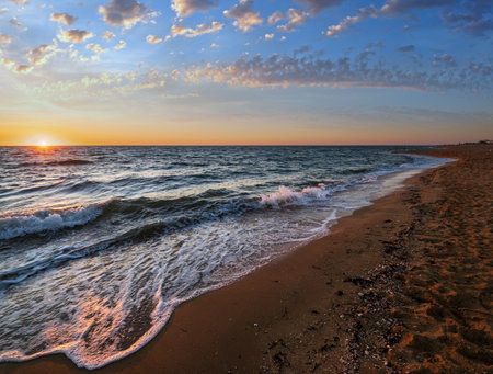 Colorful sea beach sunrise with clear morning sky and sun over horizonの写真素材