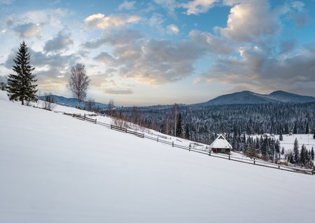 Countryside hills, groves and farmlands in winter remote alpine mountain village, and small old abandoned house on hillsideの写真素材